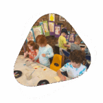 A group of children sitting at tables with papers.