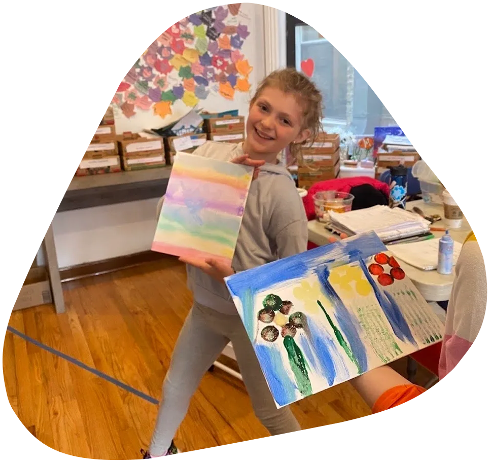 A girl holding up two paintings in front of her.